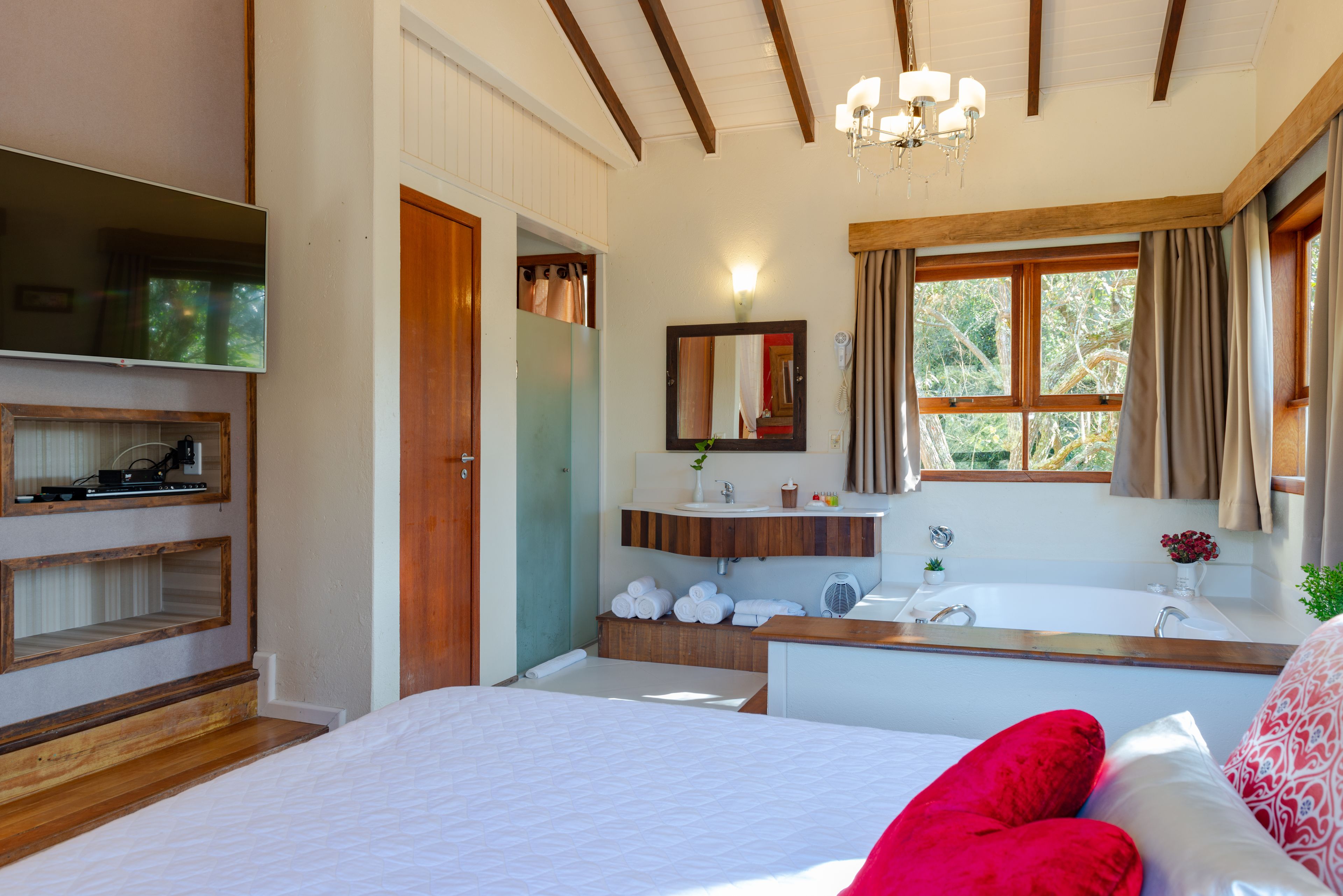 Un dormitorio con una cama grande, un cabecero de madera, un tocador con espejo, una ventana con cortinas y un ventilador de techo.