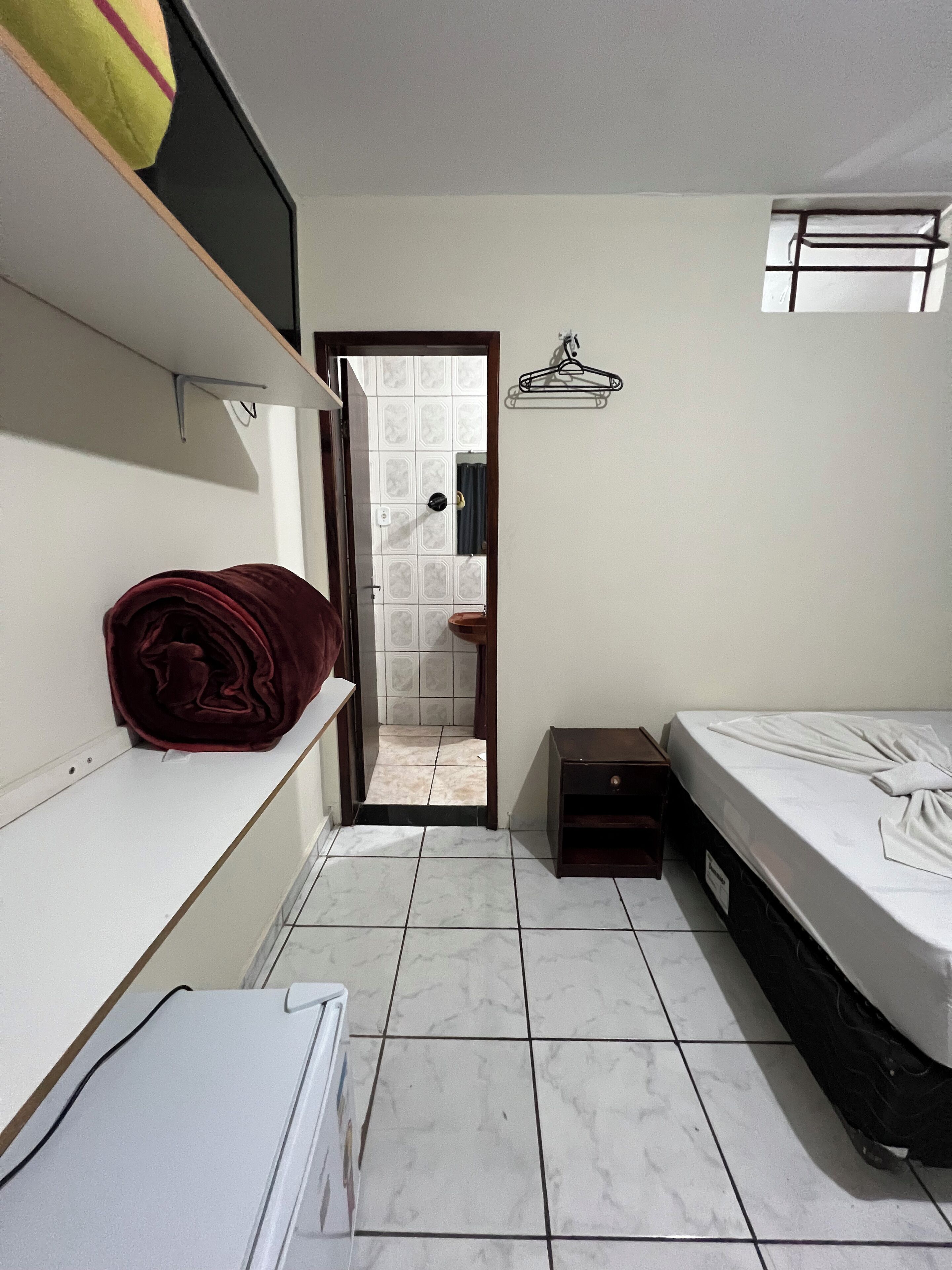 Un dormitorio con cama, mesita de noche, armario y puerta que da a un baño.