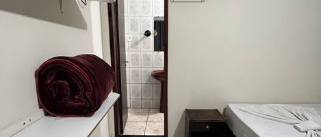 Un dormitorio con cama, mesita de noche, armario y puerta que da a un baño.