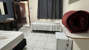 A hotel room with two beds, a desk, a chair, a mirror, a curtain, and a red blanket on a shelf.