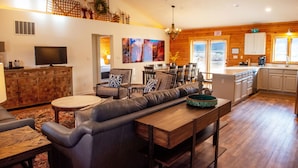 A spacious living room with a large sofa, a dining area, and a kitchen with wooden cabinets.
