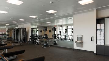 Un gimnasio con cintas de correr, balones de ejercicio y máquinas de pesas.