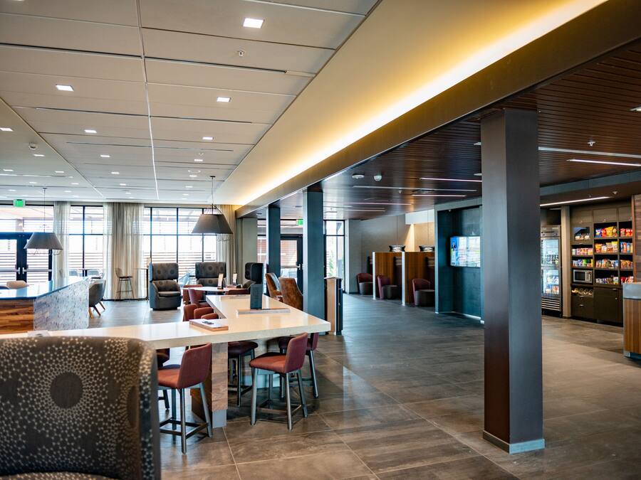 A spacious lobby with a long reception desk, multiple seating areas, and a food service counter.