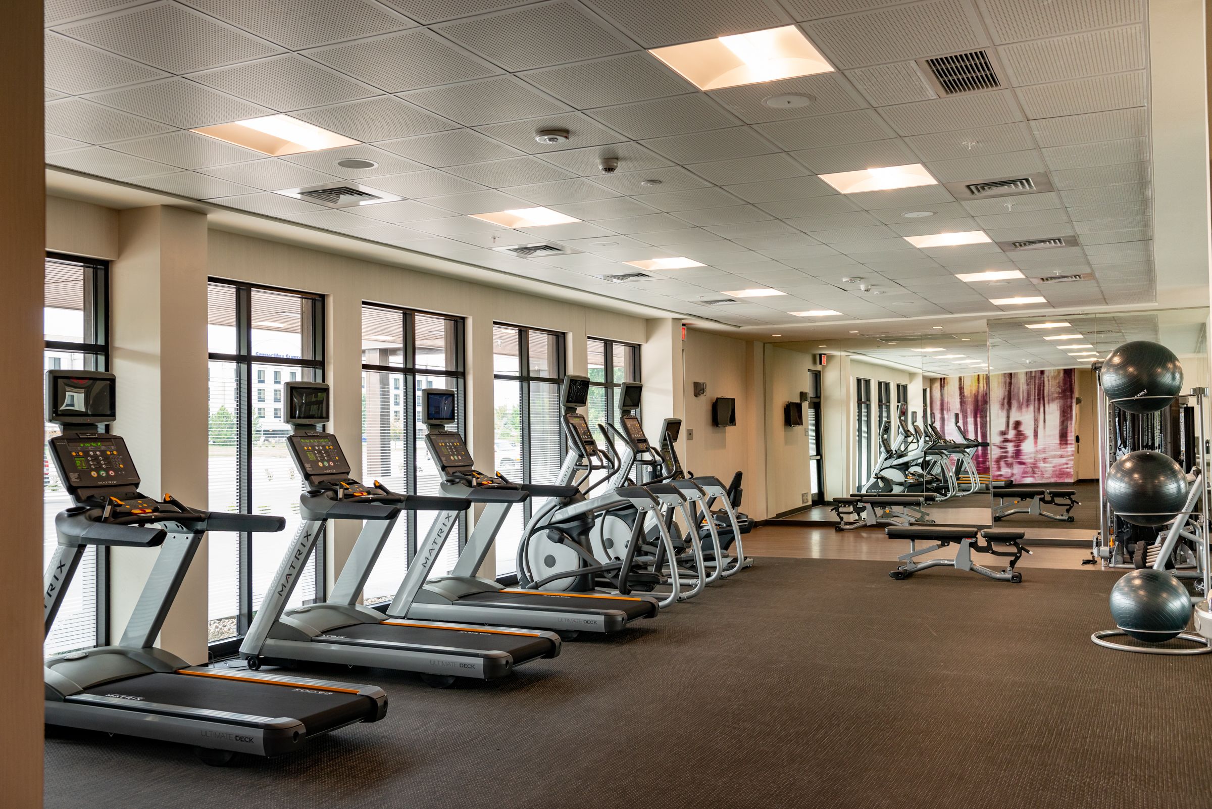 A gym with treadmills, stationary bikes, and exercise balls.