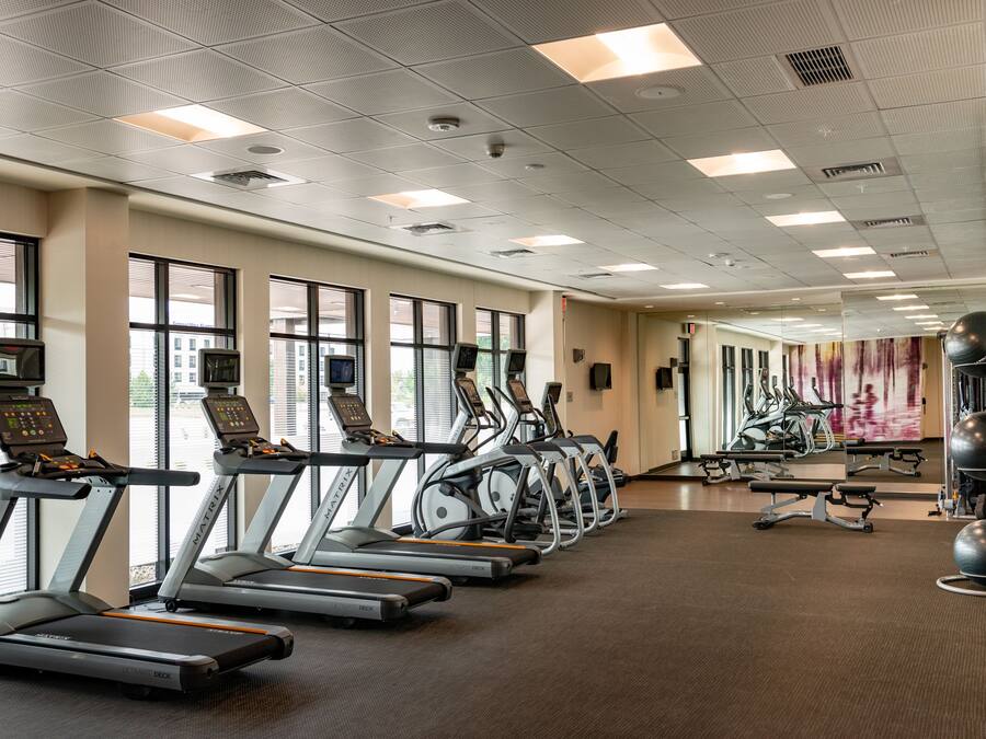 A gym with treadmills, stationary bikes, and exercise balls.