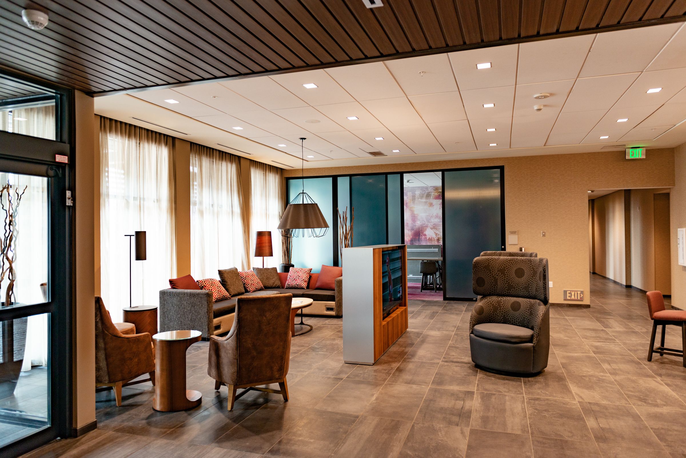 Een ruime lobby met een modern design, met een zithoek met banken en stoelen, een televisie en een receptiebalie.