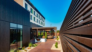 Un hôtel moderne doté d’un espace extérieur couvert avec des sièges, d’une cour et d’une clôture en bois.