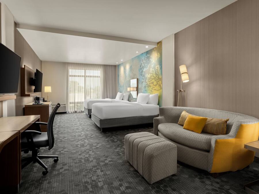 A hotel room with a bed, a sofa, a desk, and a TV.