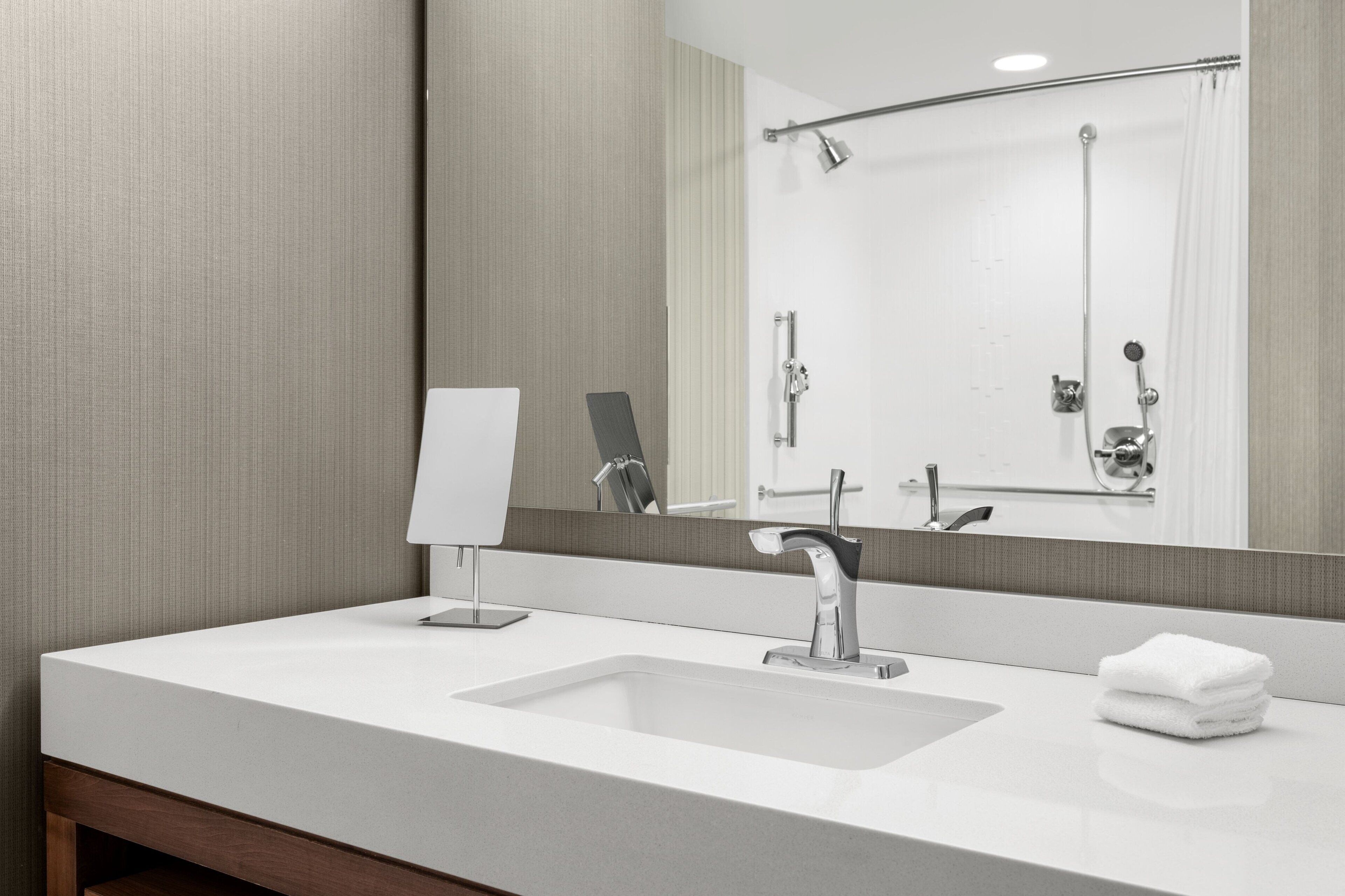 A modern bathroom with a white sink, a mirror, and a shower.
