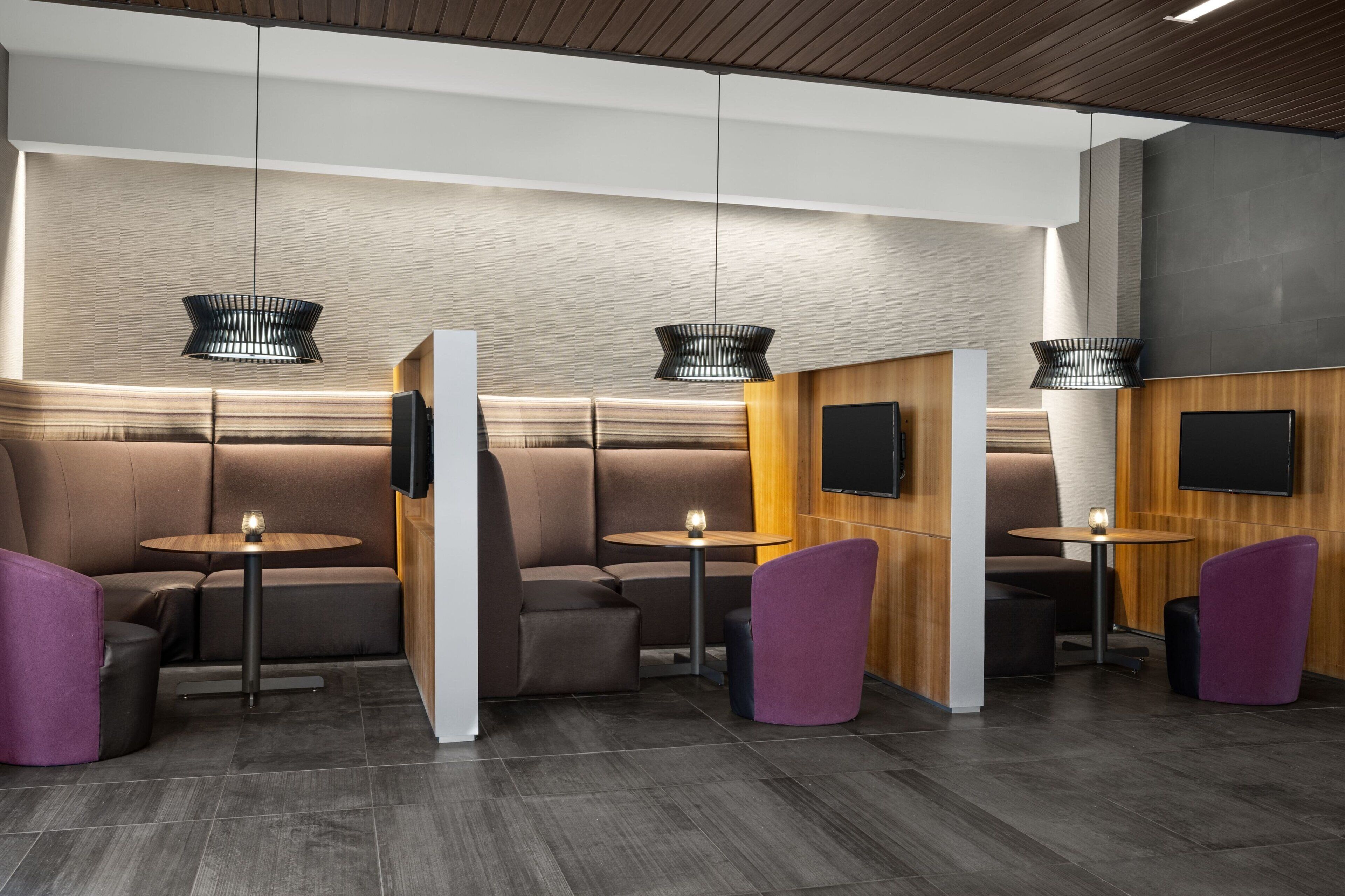 Un espace de détente moderne avec des sièges confortables, des tables rondes et des luminaires suspendus.