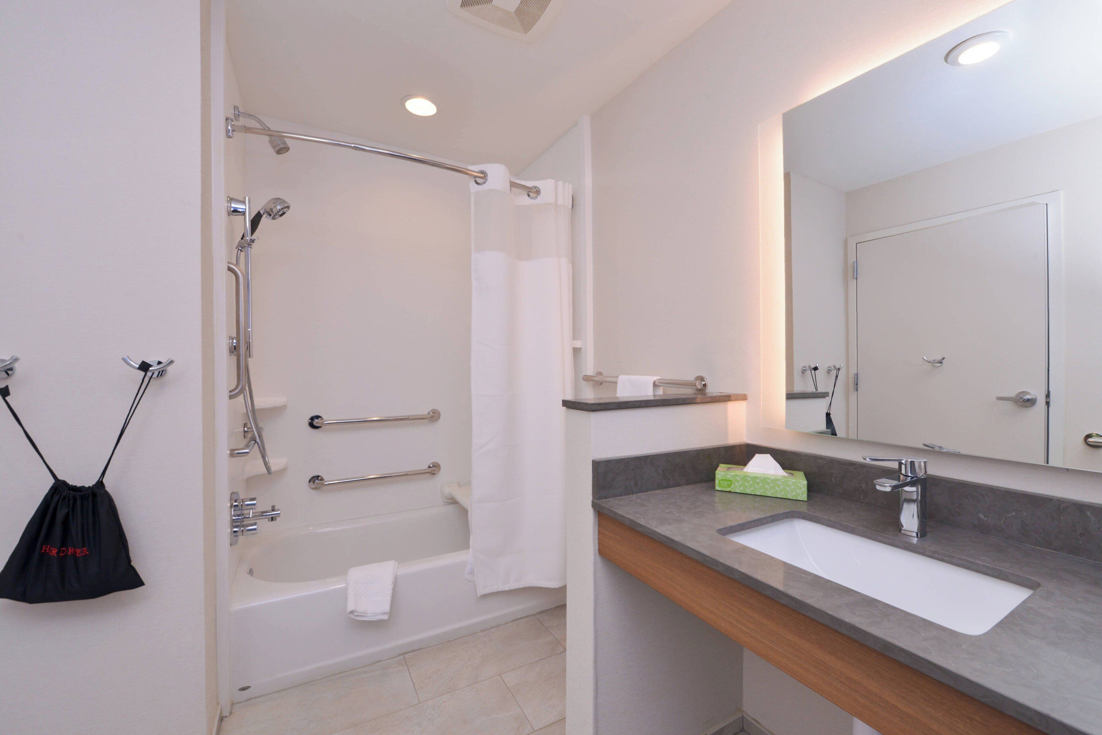 Een moderne badkamer met bad, douche en wastafel.