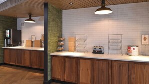 Un área de cocina moderna con armarios de madera, una encimera blanca y varios electrodomésticos.