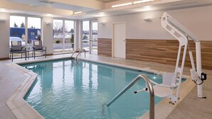 Una piscina interior con agua cristalina, una silla de socorrista y vistas al exterior a través de amplios ventanales.