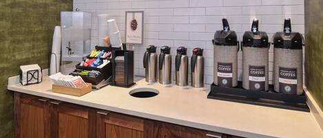 A coffee station with multiple coffee dispensers and a coffee machine.