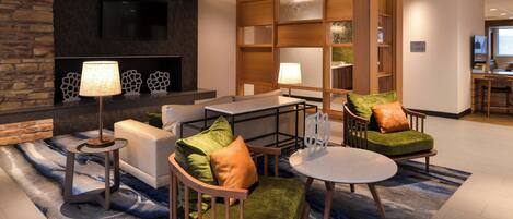 A modern lounge area with a sofa, armchairs, a coffee table, and a fireplace.