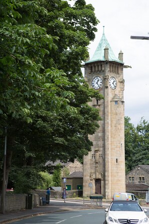A clock tower with a green roof and two clocks. - Plover Cottage (Huddersfield)