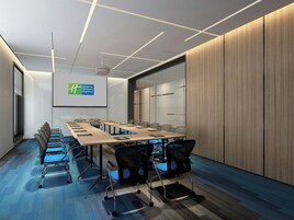 Un salón de conferencias con una larga mesa, sillas, una pantalla de proyector y un revestimiento de pared de madera.