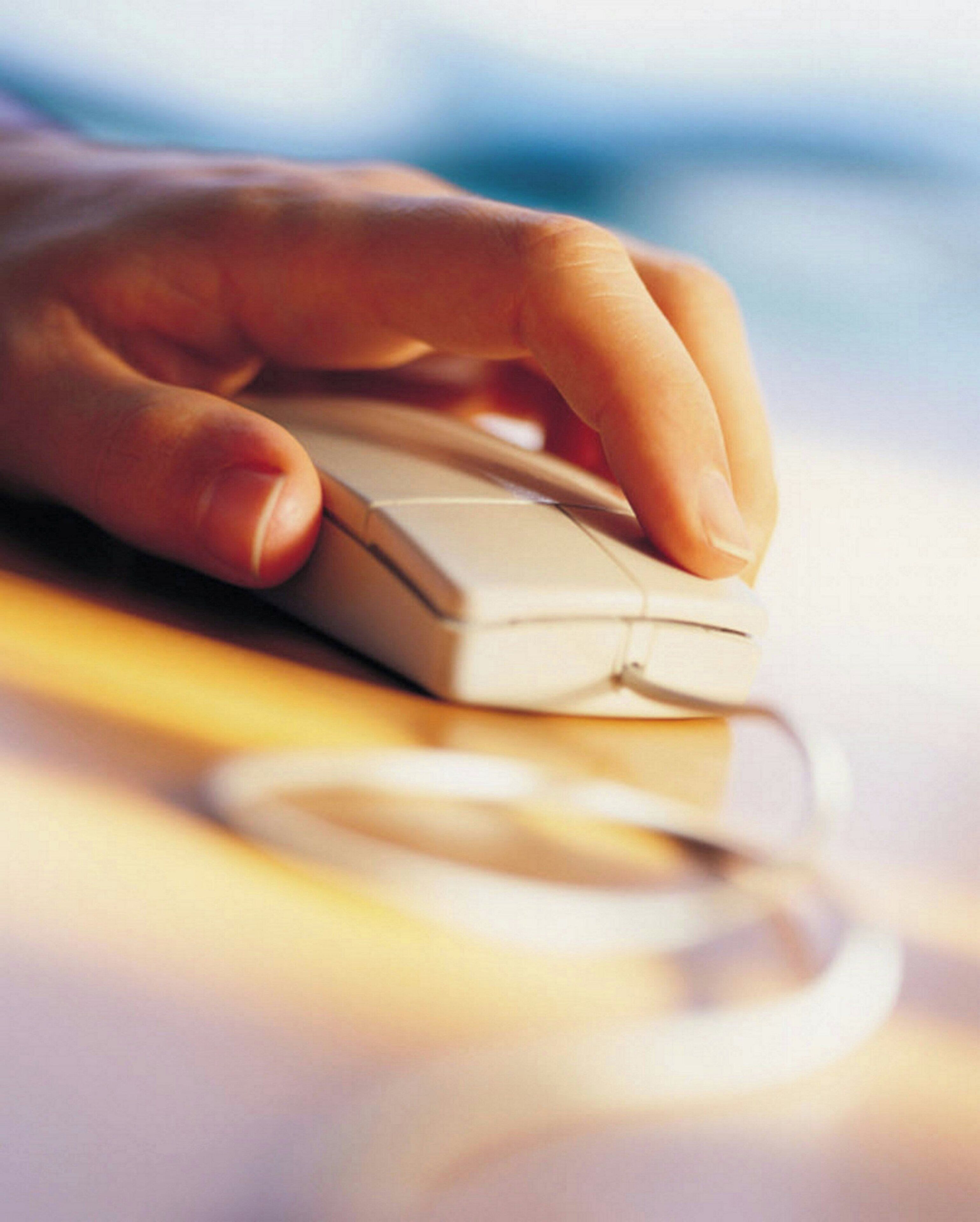 A hand using a computer mouse on a desk.