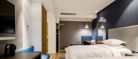 A modern hotel room with a large bed, a desk, and a TV.