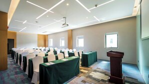 A conference room with rows of tables, chairs, and a podium.