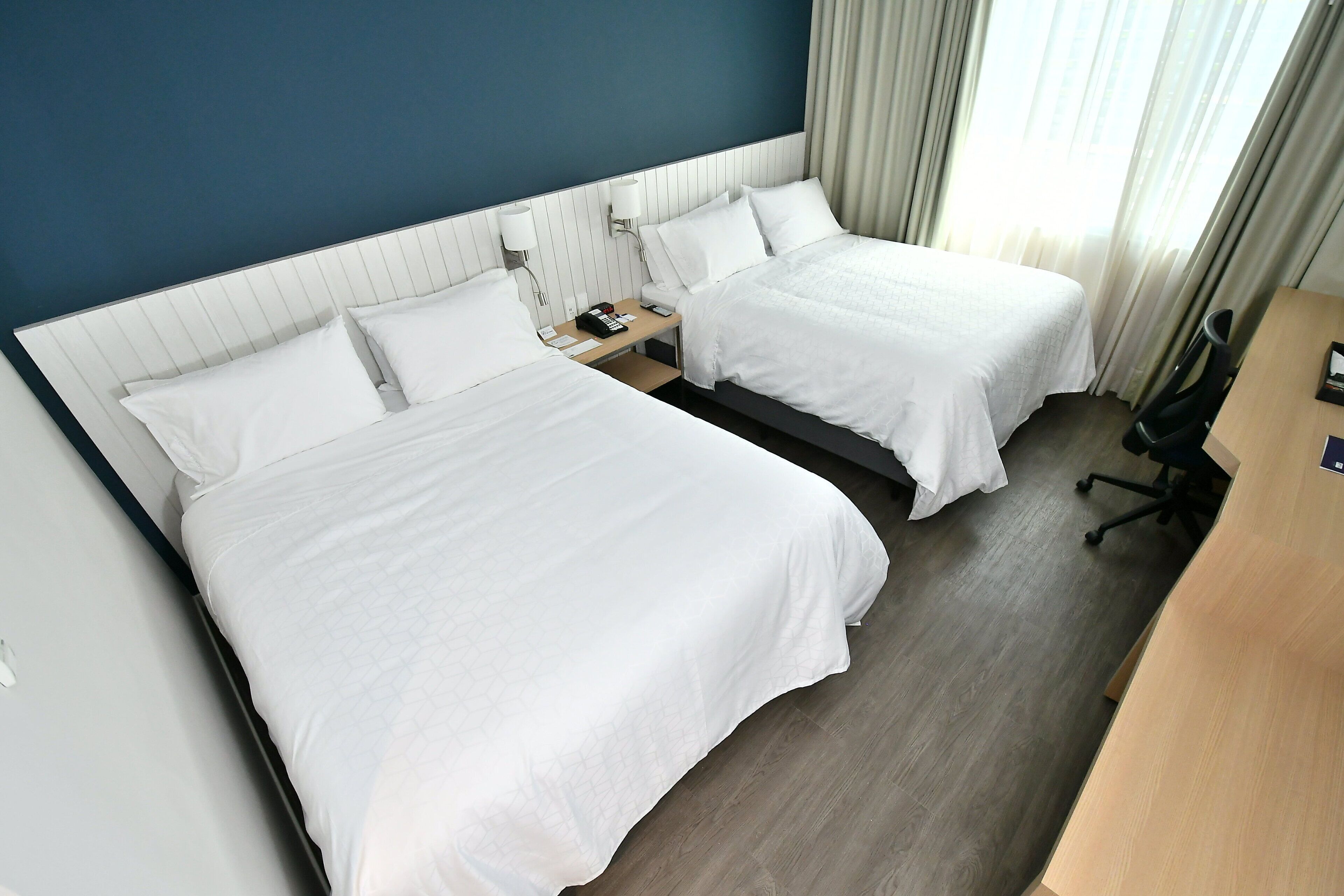 Habitación de hotel con dos camas, un escritorio y una silla.