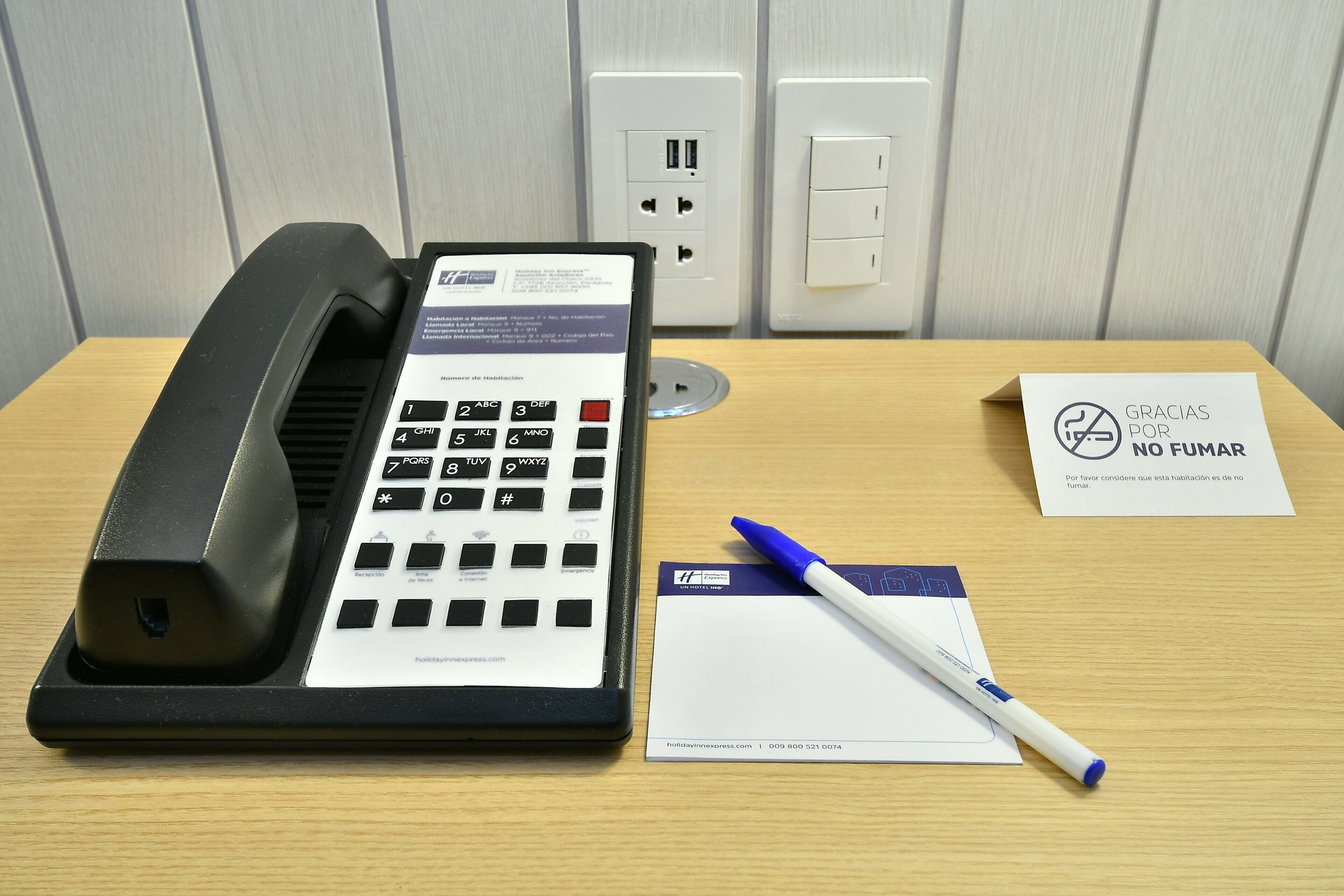 A hotel reception desk with a telephone, a notepad, and a marker.