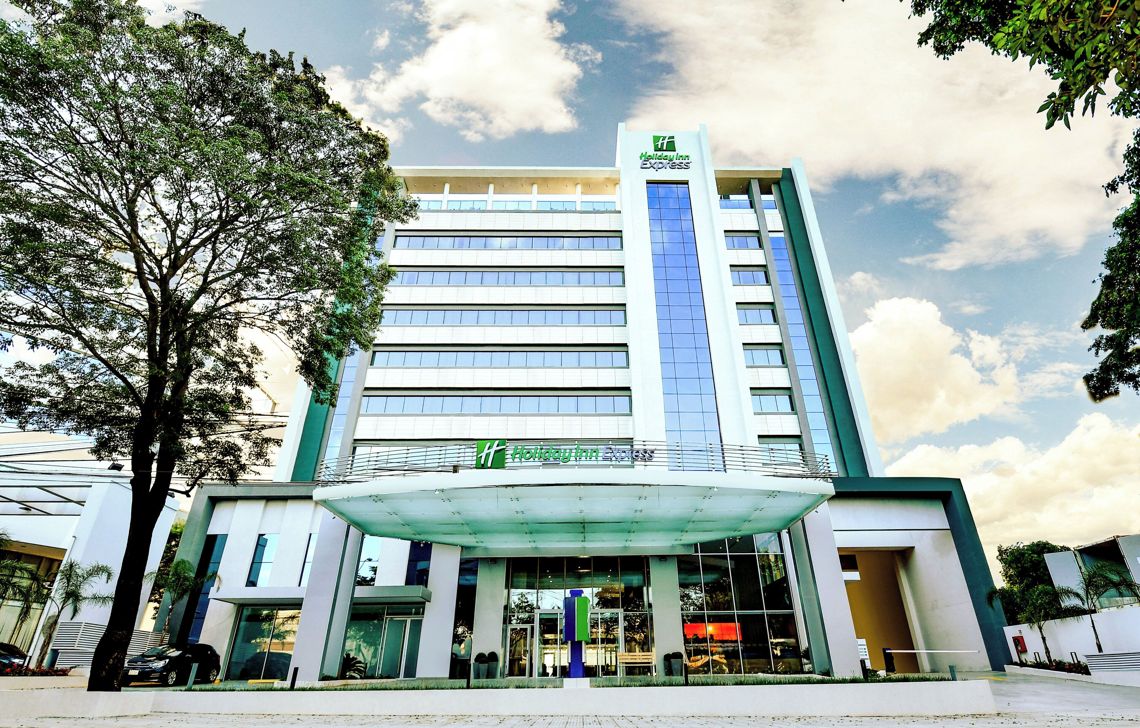 A multi-story Holiday Inn Express hotel with a prominent entrance and a clear sky.