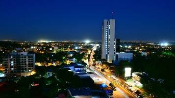 A nighttime cityscape with a prominent high-rise building and a busy street.