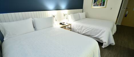 A hotel room with two beds, a nightstand, and a framed picture on the wall.