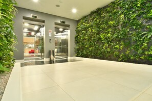 An indoor area with a green wall, a reception desk, and an elevator. - Holiday Inn Express Asuncion Aviadores by IHG (Asunción)