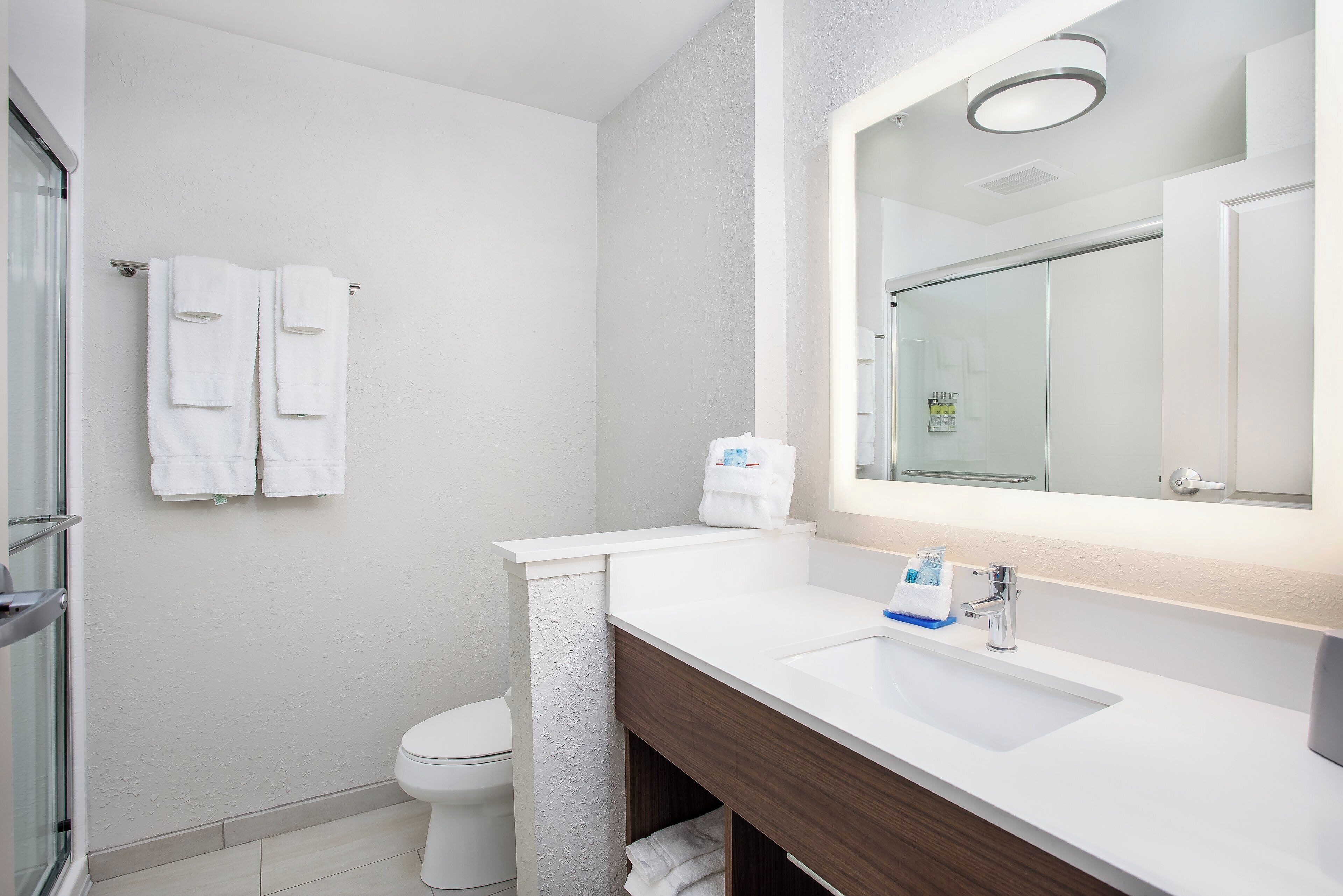 A modern bathroom with a white sink, a mirror, and a toilet.