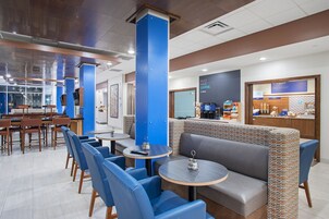 Un caf é moderno con asientos azules y grises, una barra de café y vistas a la ciudad.