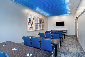 A conference room with tables and chairs, a flat-screen TV, and artwork on the wall. - Holiday Inn Express & Suites Lexington W - Versailles by IHG (Versailles)