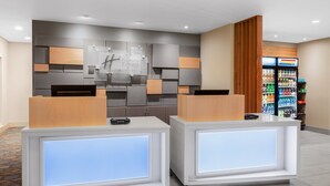 A hotel reception area with two reception desks, a wall-mounted sign, and a beverage refrigerator. - Holiday Inn Express and Suites Union Gap- Yakima Area by IHG (Yakima)