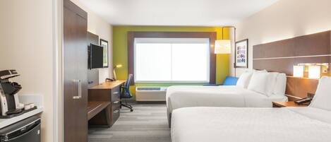 A hotel room with a bed, desk, chair, and a coffee machine.