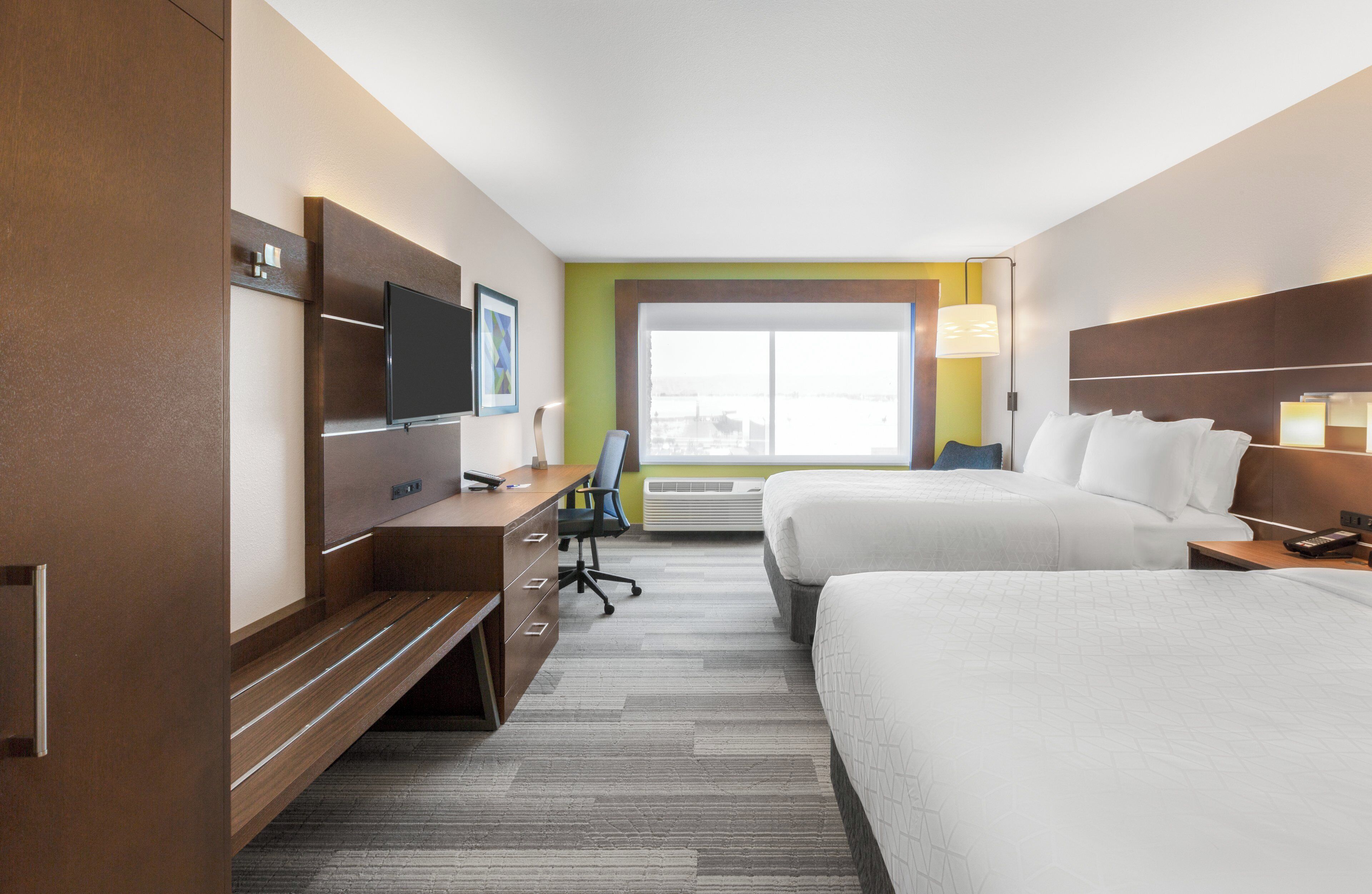 A hotel room with a bed, a desk, a television, and a window.