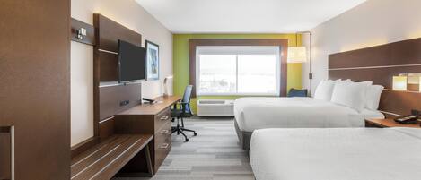 Una habitación de hotel con cama, escritorio, televisor y ventana.