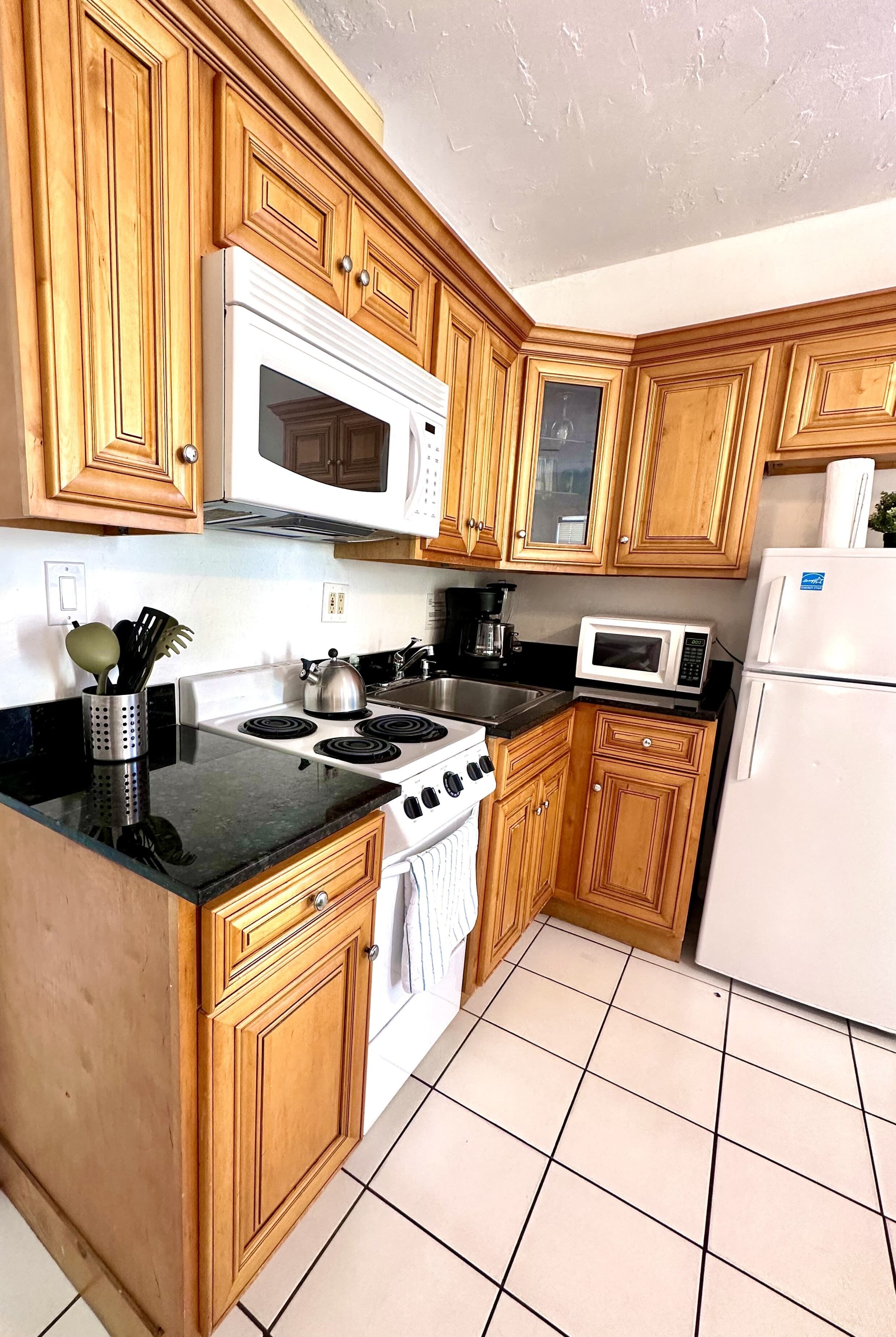 A kitchen with wooden cabinets, a stove, a microwave, and a refrigerator.