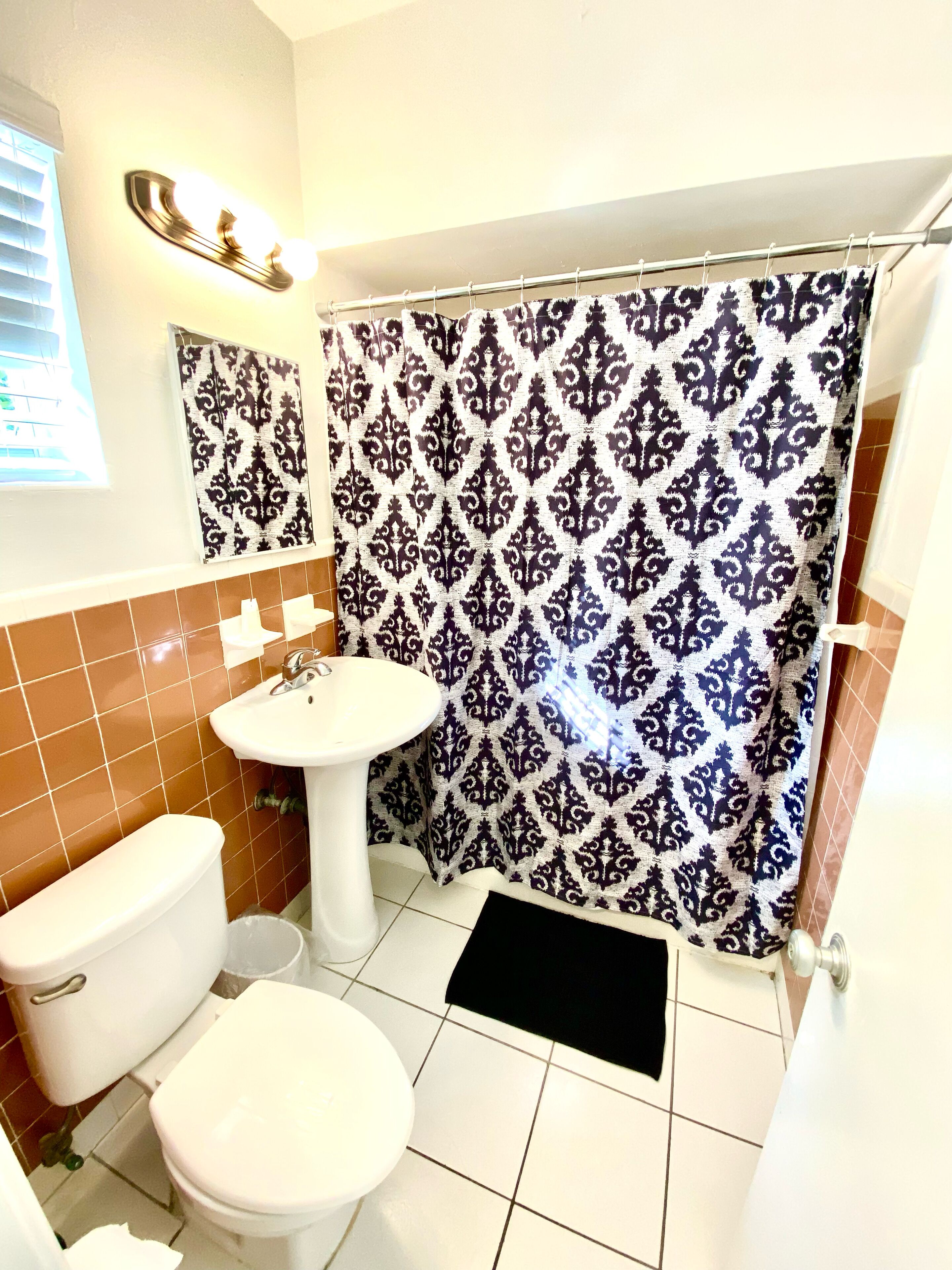 A bathroom with a toilet, sink, and shower curtain.