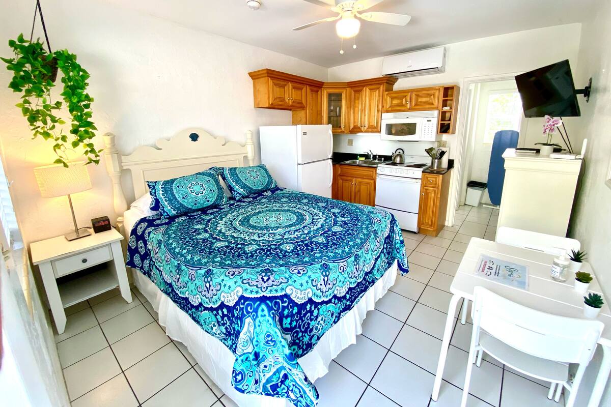 A bedroom with a bed, nightstand, and a desk with a chair.