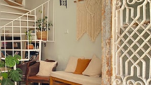Una sala de estar con sofá, una estantería y un panel decorativo en la pared.