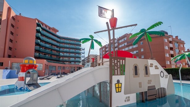 A swimming pool with a bridge, palm trees, and a lifeguard stand. - Fenals Garden (Lloret de Mar)