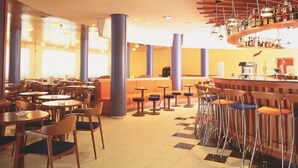 A spacious hotel lobby with multiple seating areas, a central bar, and a large window providing natural light. - Fenals Garden (Lloret de Mar)