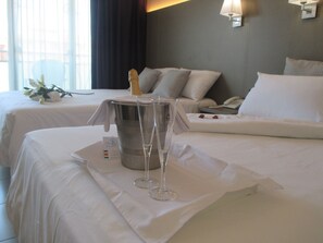 Habitación de hotel con dos camas, un minibar, un teléfono y una ventana con cortinas.