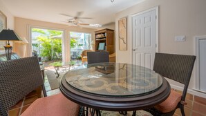 A dining area with a glass-top table, wicker chairs, and a ceiling fan. - Sago Palm at The Truman Annex in Key West (Key West)