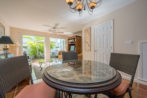 A dining area with a glass-top table, wicker chairs, and a ceiling fan.