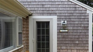A house with a grey door, a window, a welcome sign, and a flower pot on the porch. - Cozy Cockle Cove Retreat! (South chatham)