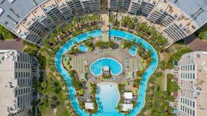 An aerial view of a hotel with a large central pool, surrounded by multiple smaller pools and sun loungers. - Destin West 512 * Beach Chair Set Included * Salt Water Vacations (Fort Walton Beach)