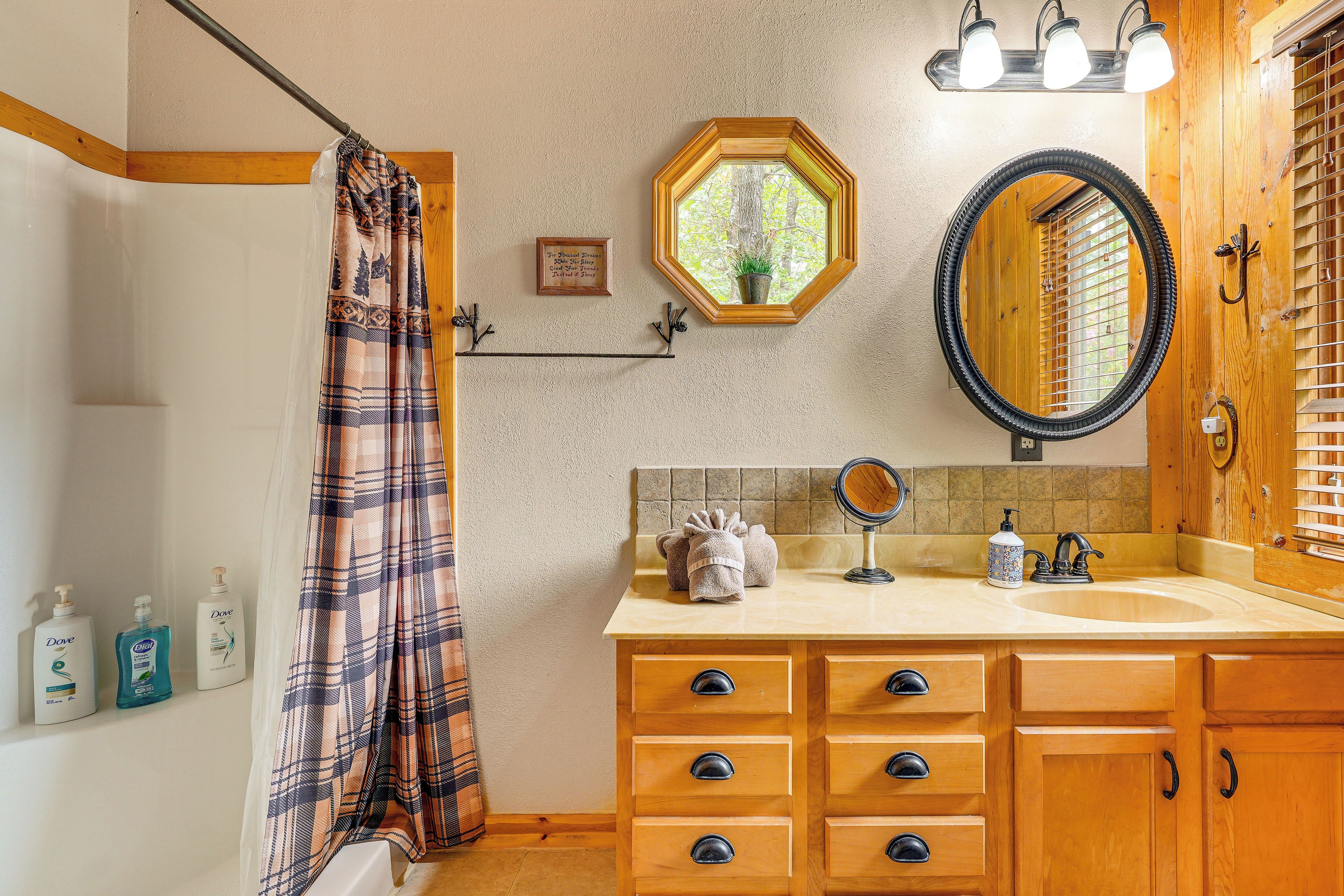 A bathroom with a shower curtain, a sink with a mirror, and toiletries on the wall.