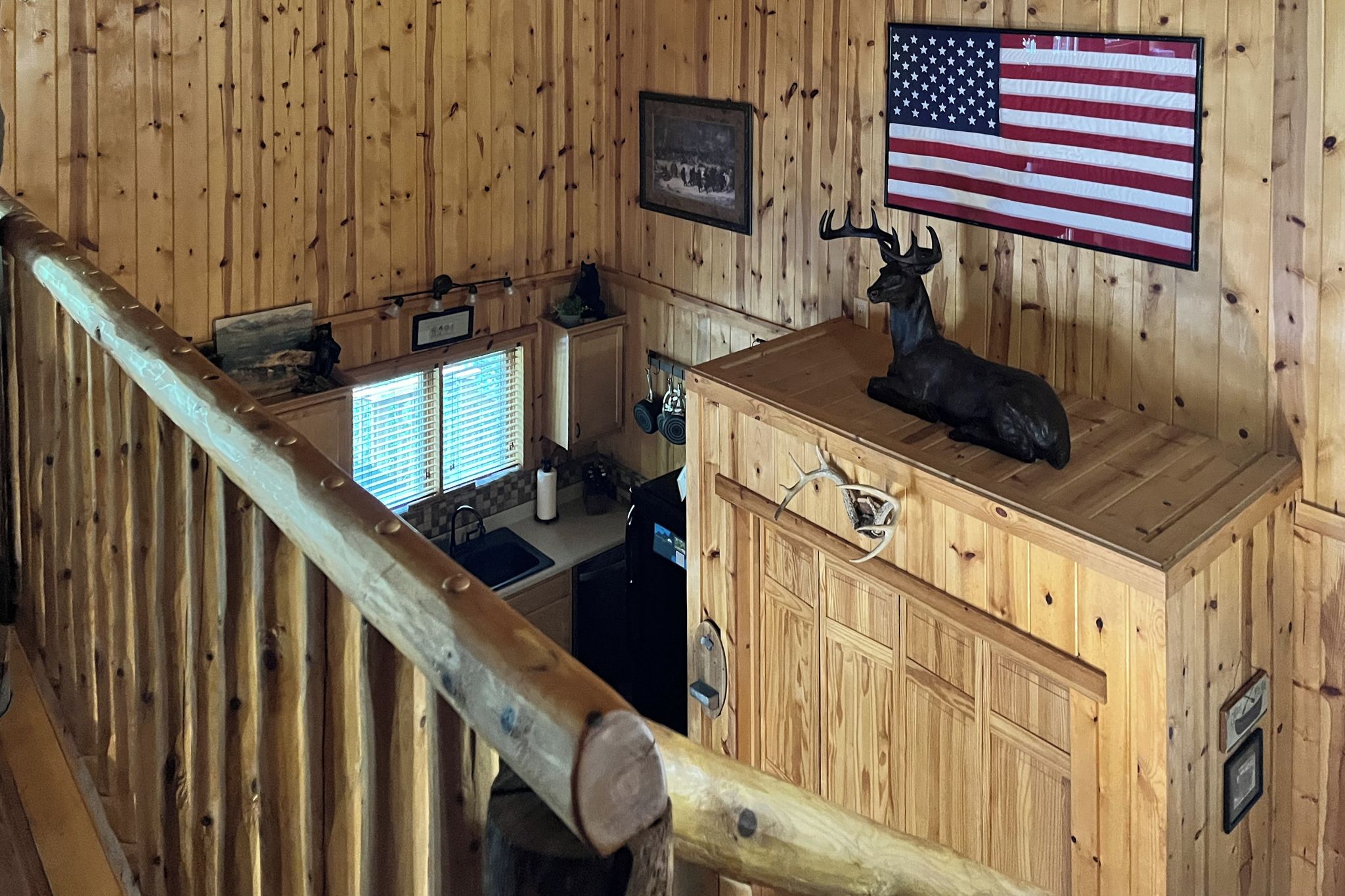 A wooden interior with a flag, a statue, and a kitchen area.